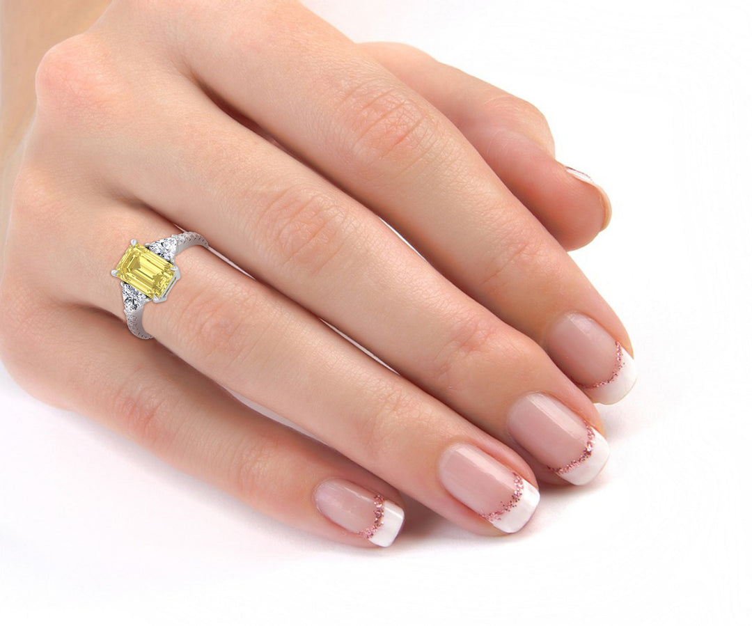 Hand wearing a ring with a yellow gemstone on a white background