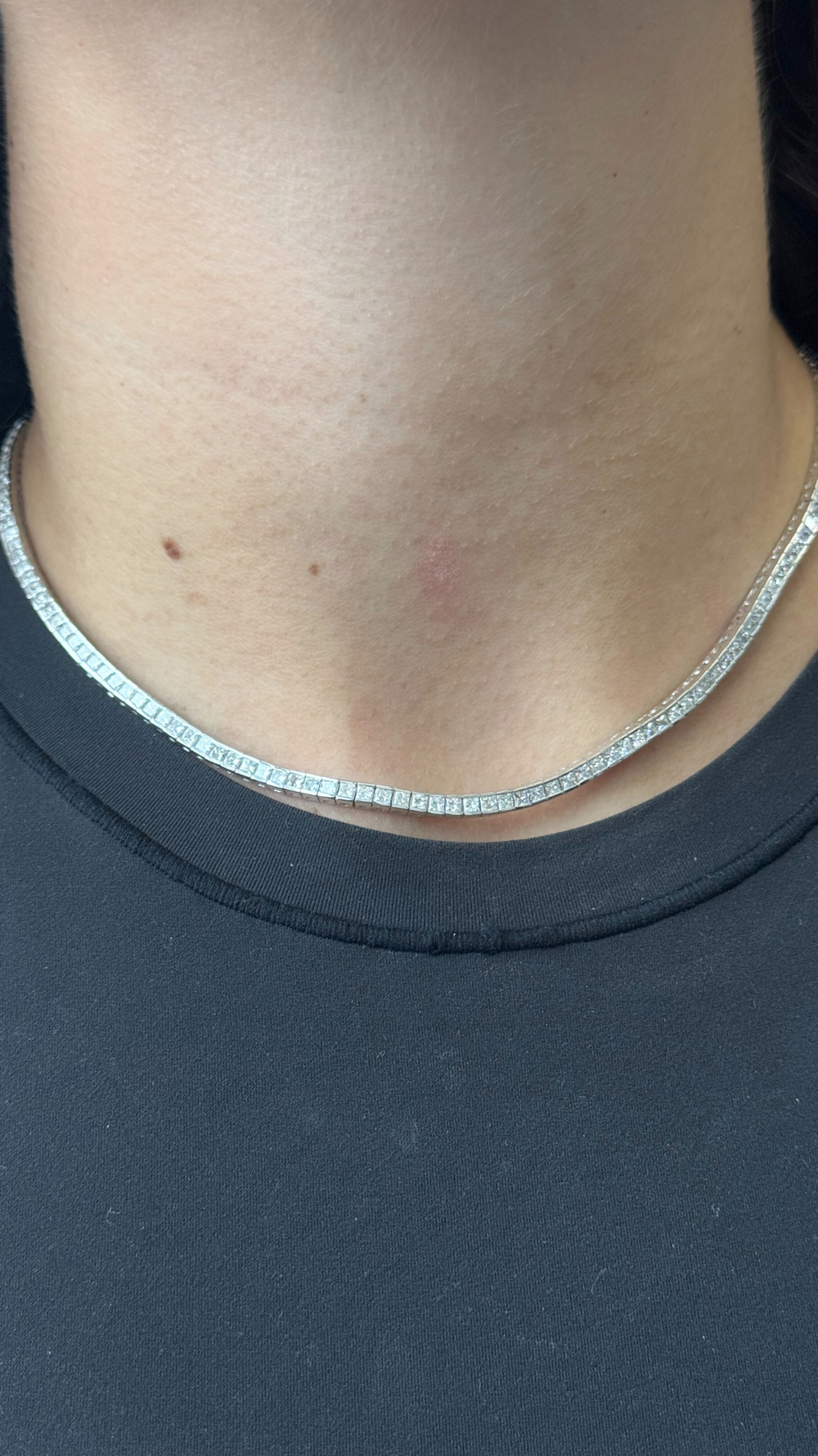 Silver chain necklace on a person wearing a black shirt