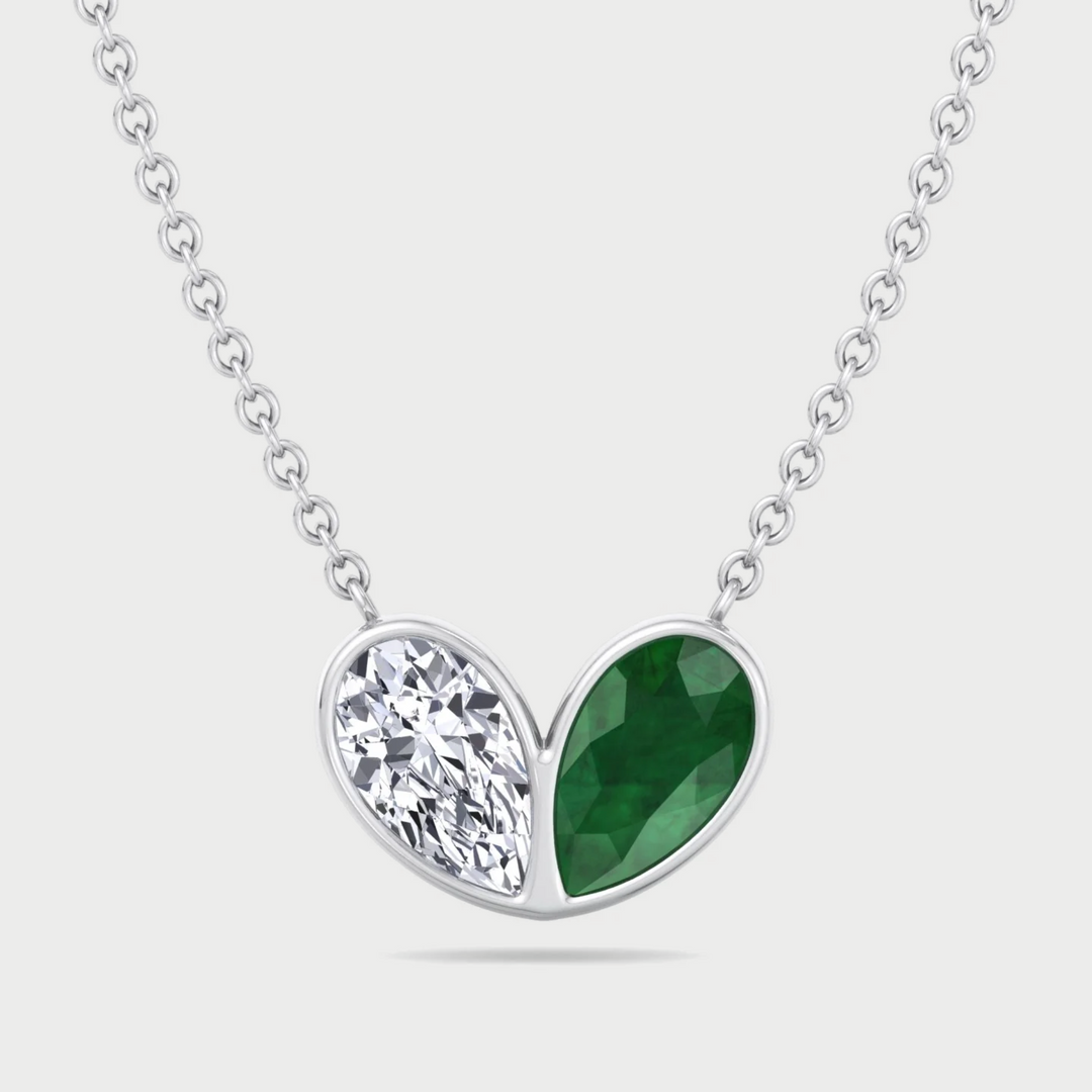 Necklace with a heart-shaped pendant featuring a green gemstone and clear crystal on a white background