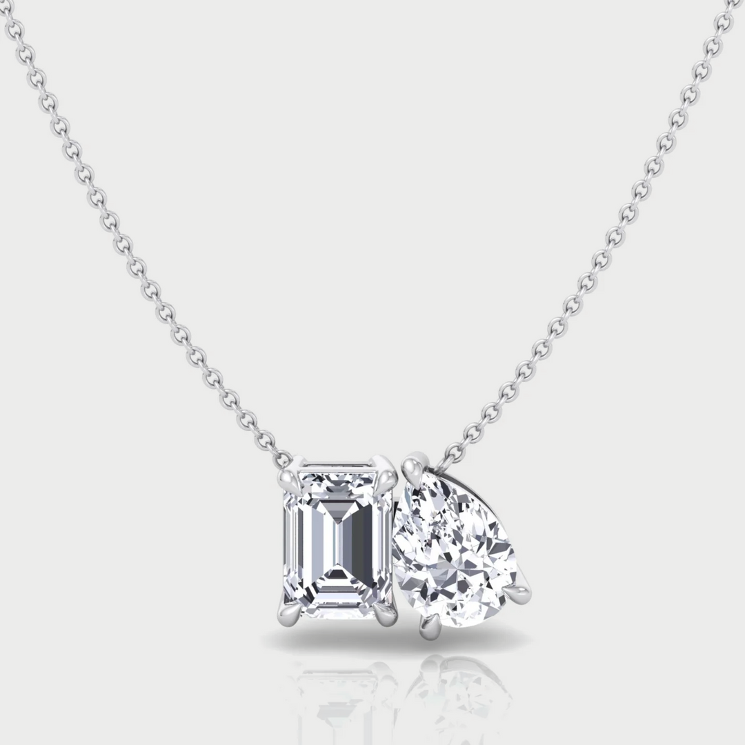 Diamond necklace with two different shaped diamonds on a light gray background