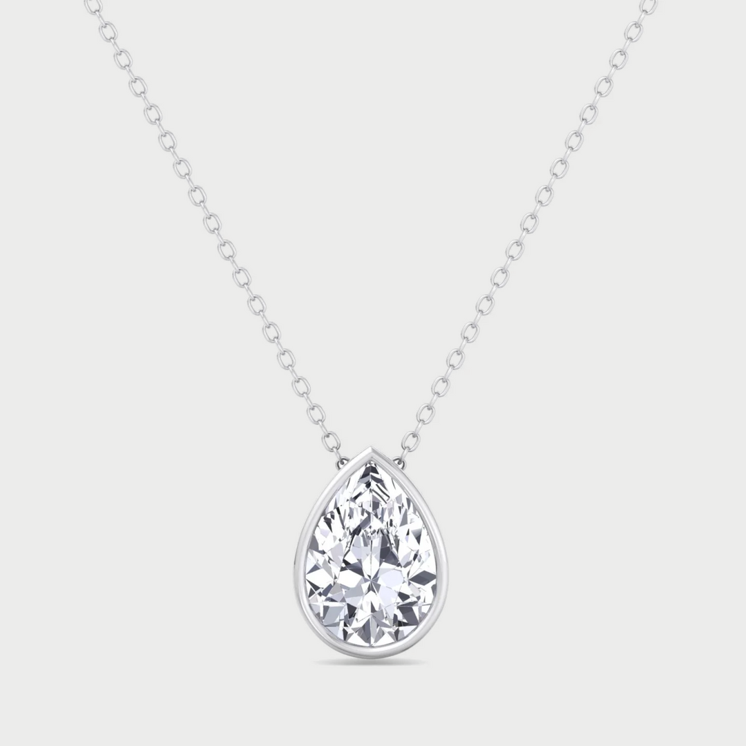 Teardrop-shaped diamond pendant on a chain against a light gray background