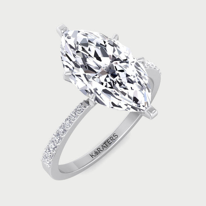 Diamond ring with a large central gemstone and smaller stones on the band, on a light gray background.