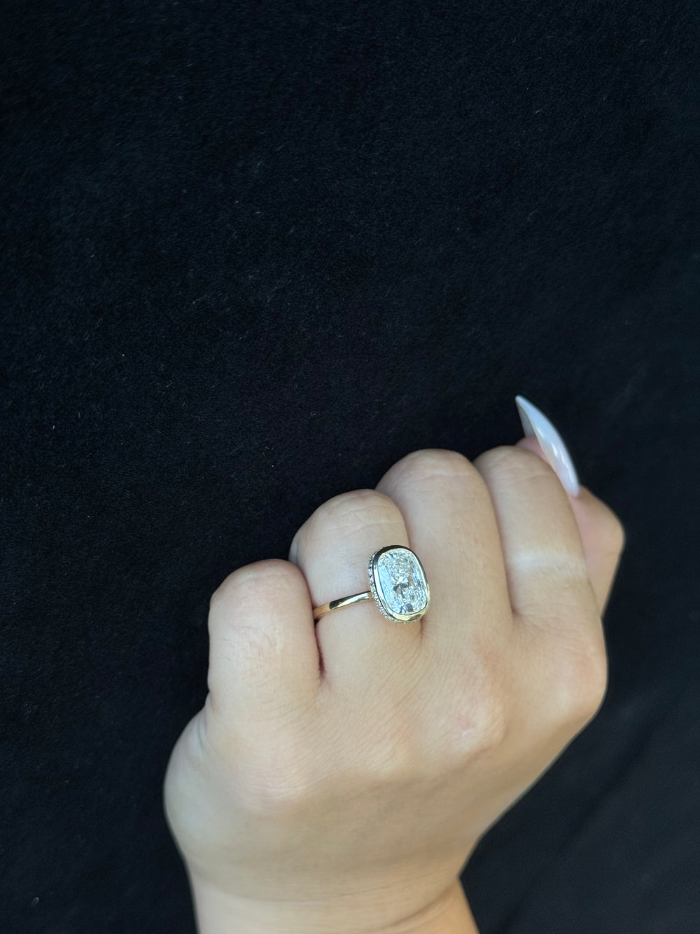 Hand wearing a ring with a diamond on a black background