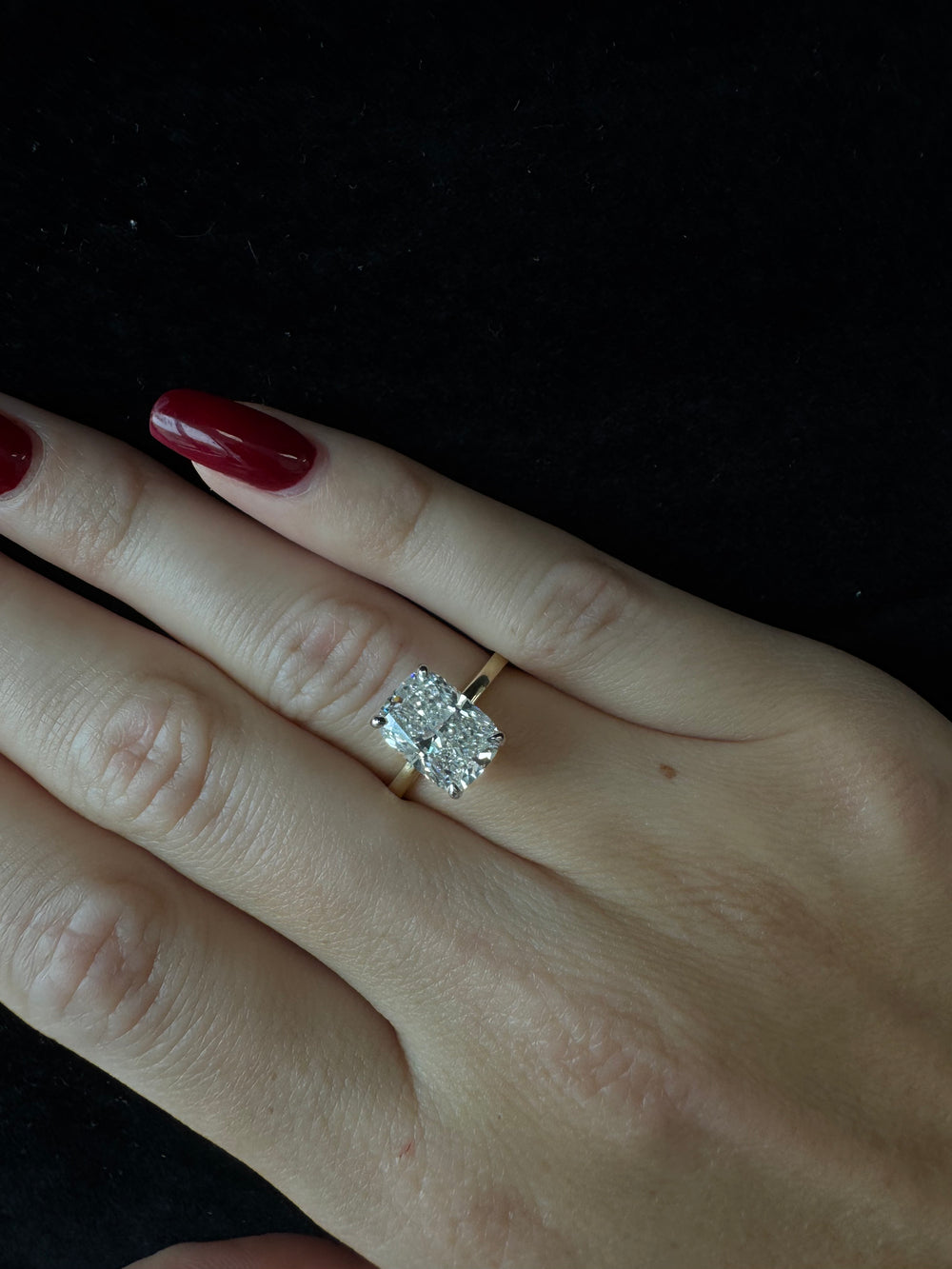 Diamond ring on a finger with a dark background
