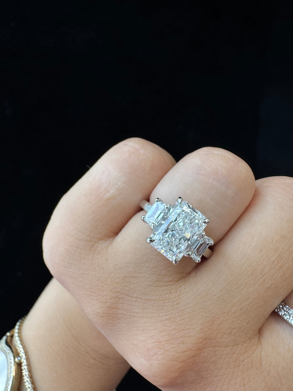 Diamond ring on a finger against a dark background