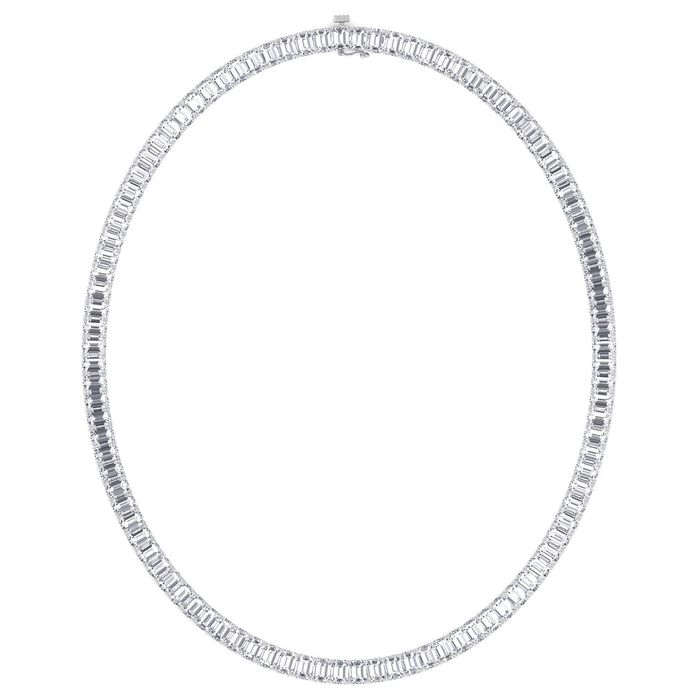 A tennis necklace with emerald cut lab-grown diamonds set in a gold chain against a light green background.