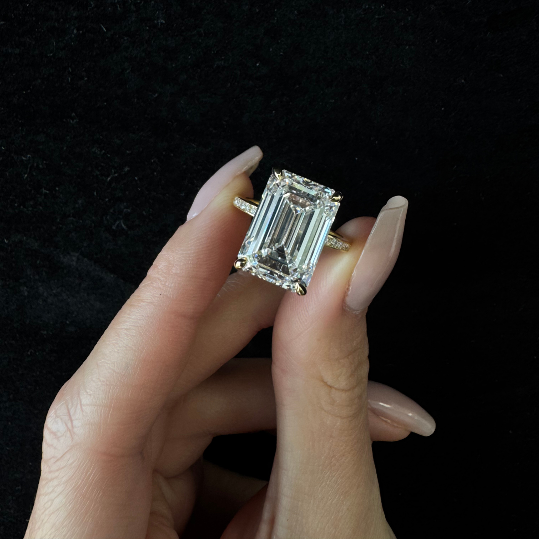Diamond ring held by a hand against a black background