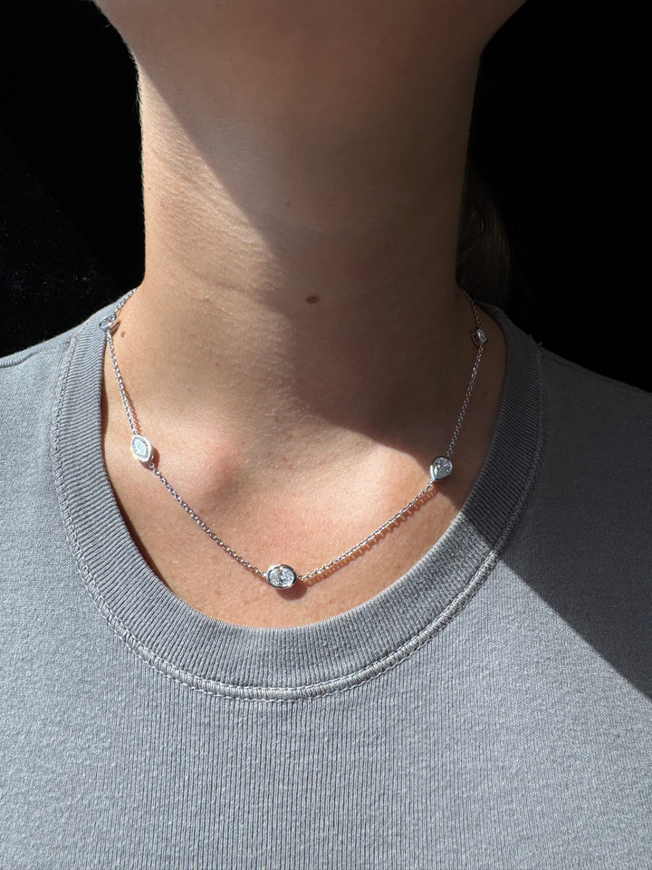 Silver anklet on a person's ankle against a gray background